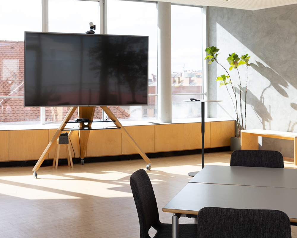 Workshop-Setup im Level mit großem Bildschirm, Tischen und Sesseln
